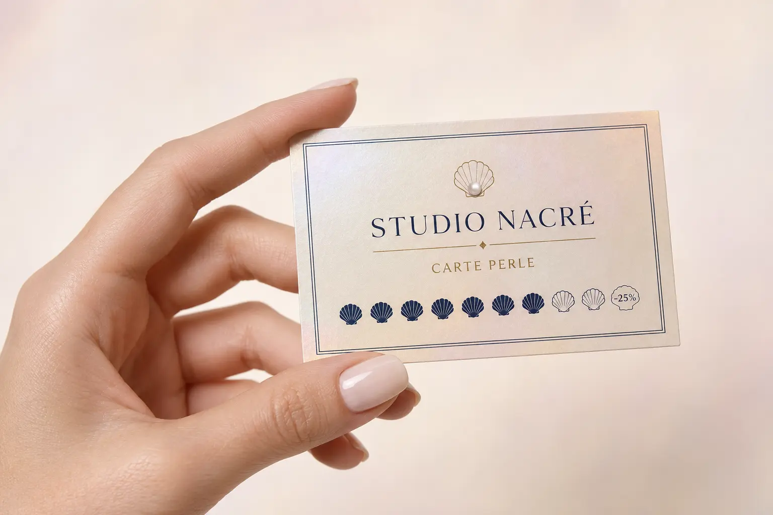 Une main manucurée tenant la carte de fidélité Carte Perle de Studio Nacré